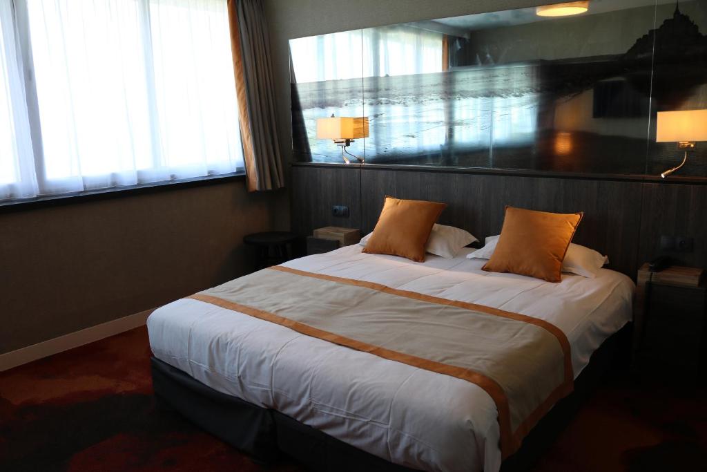 a hotel room with two beds and a window at Hotel De La Digue in Le Mont Saint Michel