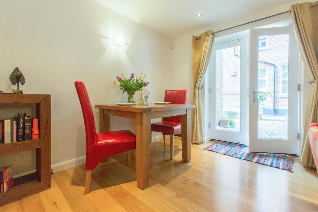 a dining room with a table and two red chairs at Stones Throw in Aldeburgh
