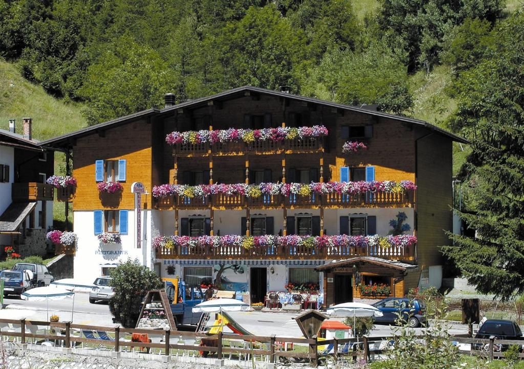 un bâtiment avec des fleurs sur ses balcons dans l'établissement Albergo Genzianella, à Rocca Pietore