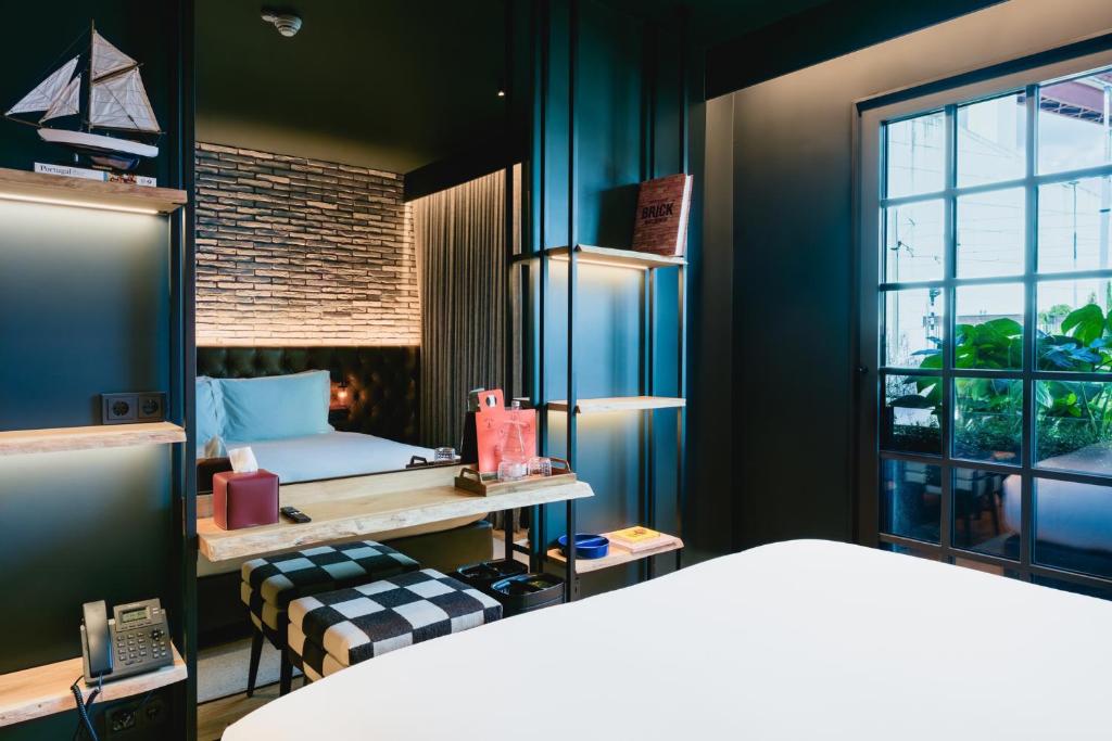 A design-focused bedroom with a bed, desk, shelving and a bright window.