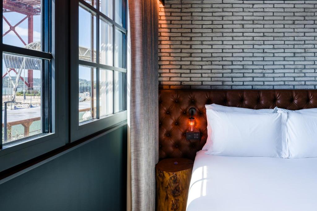 A bed beside large windows with a visible waterfront and bridge-side outlook.