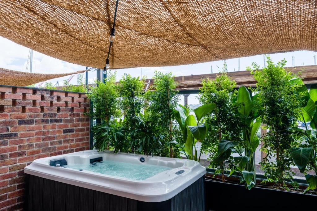 A rooftop hot tub surrounded by dense planting beneath a woven shade canopy.
