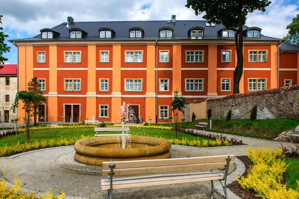 un grand bâtiment orange avec une fontaine devant lui dans l'établissement Długi Dom, à Jelenia Góra