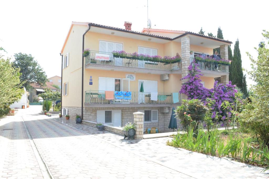 ein Gebäude mit Blumen auf den Balkonen an einer Straße in der Unterkunft Villa Bencun in Medulin