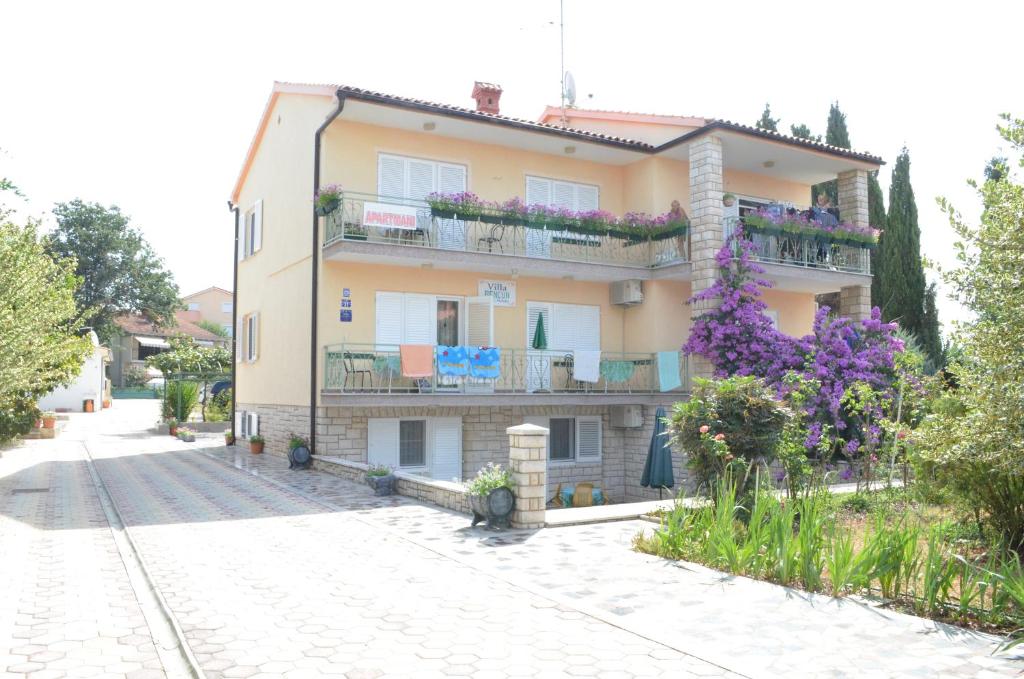 a building with flowers on the balconies on a street at Villa Bencun in Medulin