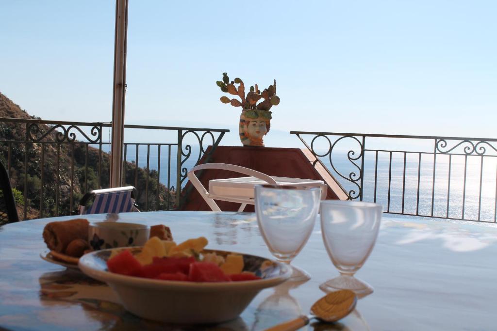 Una mesa con un bol de fruta y dos copas de vino. en Spectacular View, en Taormina