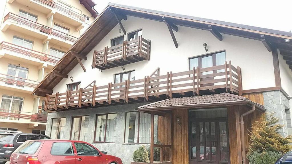 een gebouw met een balkon en een rode auto voor de deur bij Pensiunea Argesu ** in Sinaia