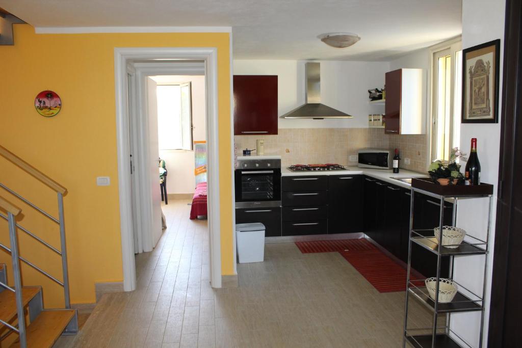 una cocina con armarios negros y una pared amarilla en Casa Vacanze Roccella Beach en Campofelice di Roccella