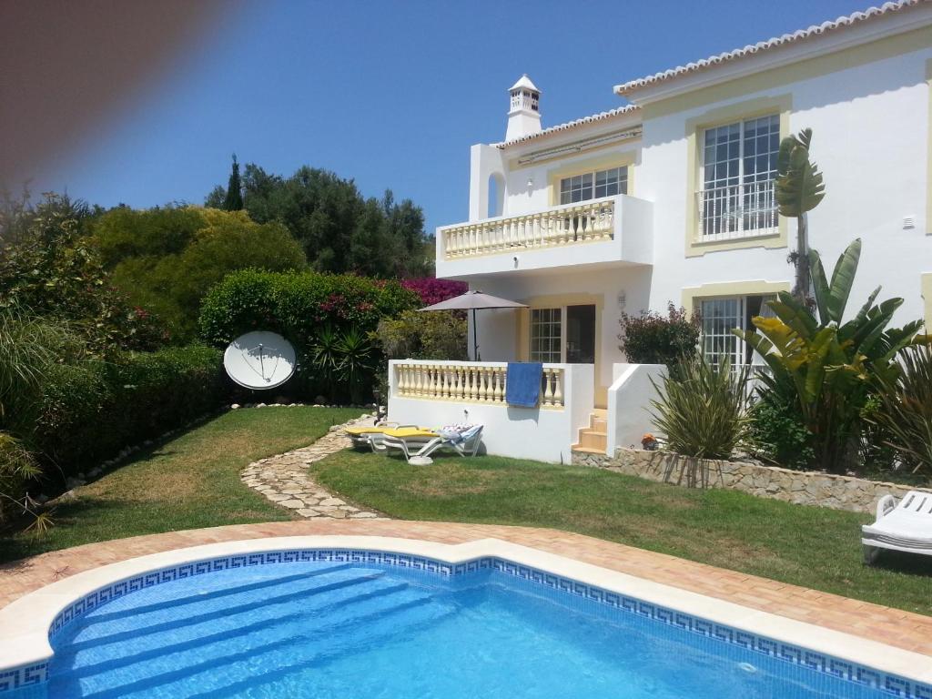 a villa with a swimming pool in front of a house at Praia da Luz Apartments in Luz