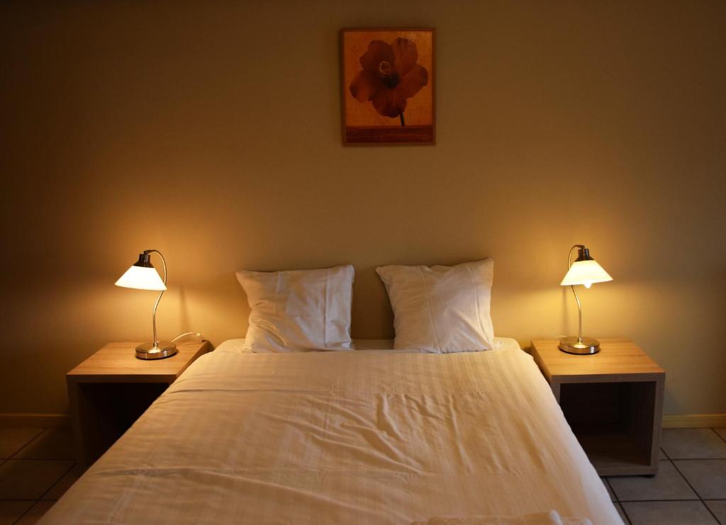 een slaapkamer met een wit bed en 2 lampen bij Condo Gardens Antwerp in Antwerpen