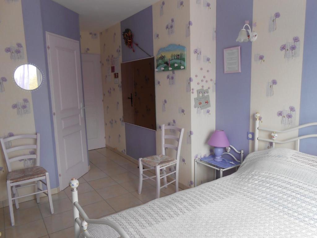 a bedroom with a white bed and two chairs at La Roche bleue in Saint-Laurent-de-la-Prée