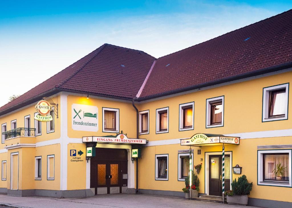 un bâtiment jaune avec un toit brun dans l'établissement Gasthof Mandorfer, à Hörsching