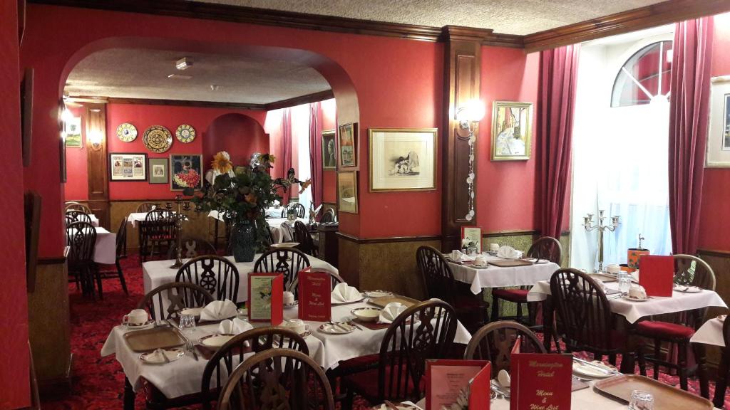 a restaurant with tables and chairs in a room with red walls at Mornington Hotel in Saint Helier Jersey
