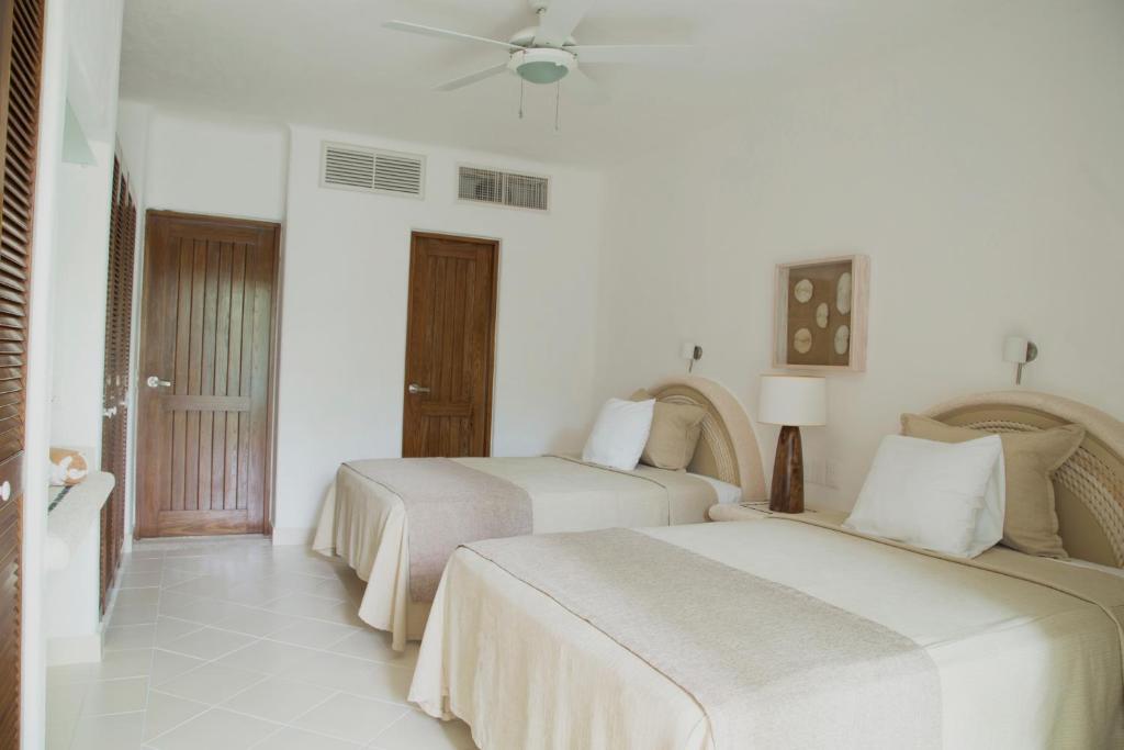 two beds in a room with white walls at Las Villas Akumal in Akumal
