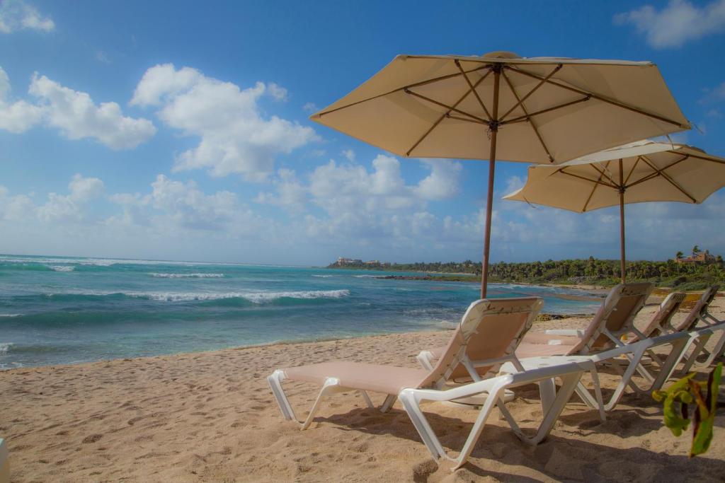 two chairs and an umbrella on a beach at Las Villas Akumal in Akumal