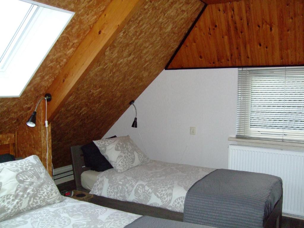 een slaapkamer met twee bedden en een raam bij De Pompstee Rolde in Rolde