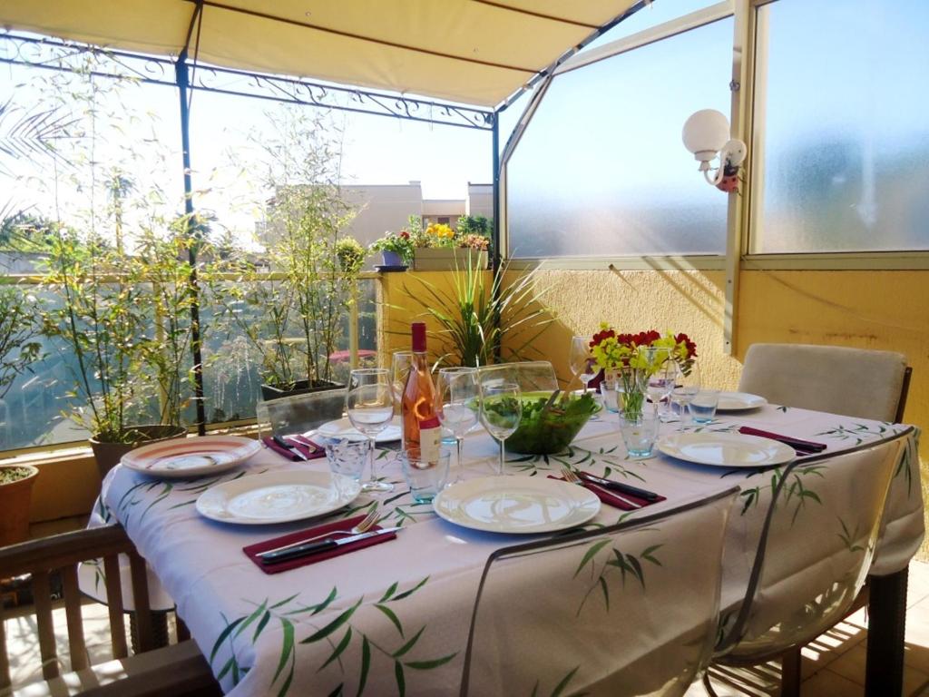 une table avec des assiettes et des verres au-dessus dans l'établissement Appartement Angela, au Golfe-Juan