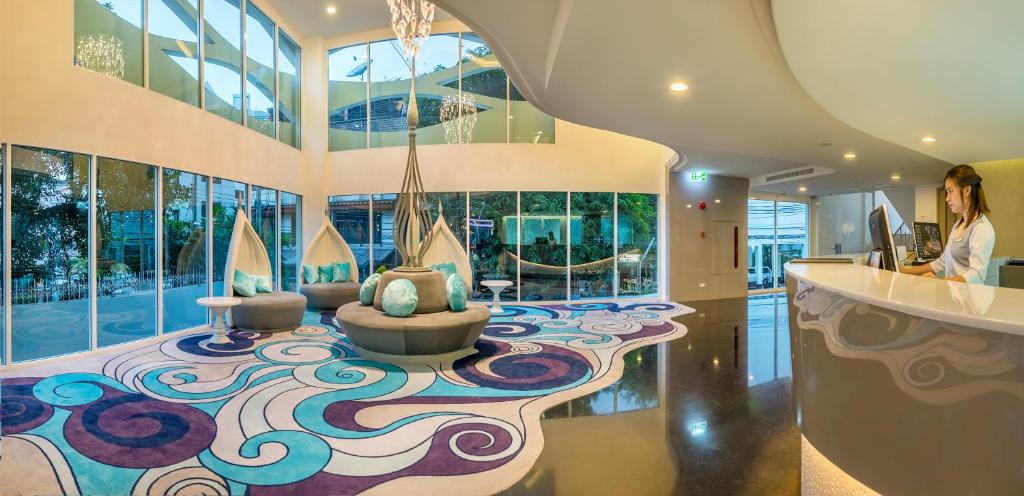 A bright hotel lobby with a sculptural reception desk and patterned carpet.