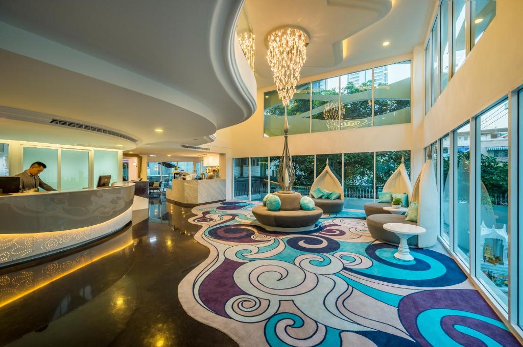 A bright double-height lobby with a curved reception desk and patterned rug.