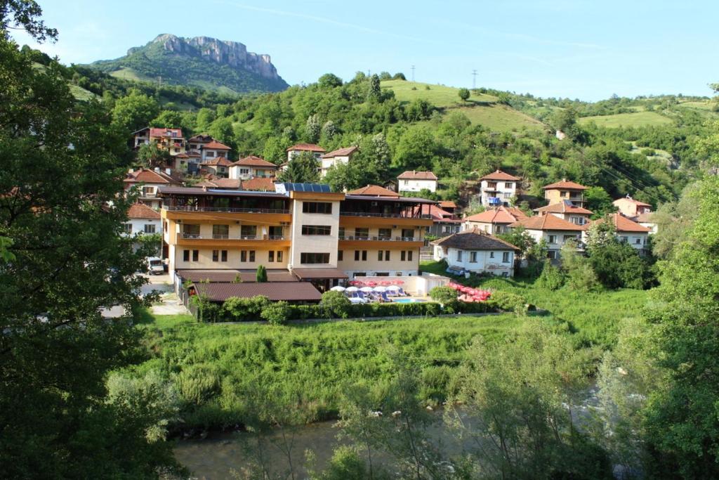 una pequeña ciudad en una colina con un río y casas en Family Hotel Enica en Teteven
