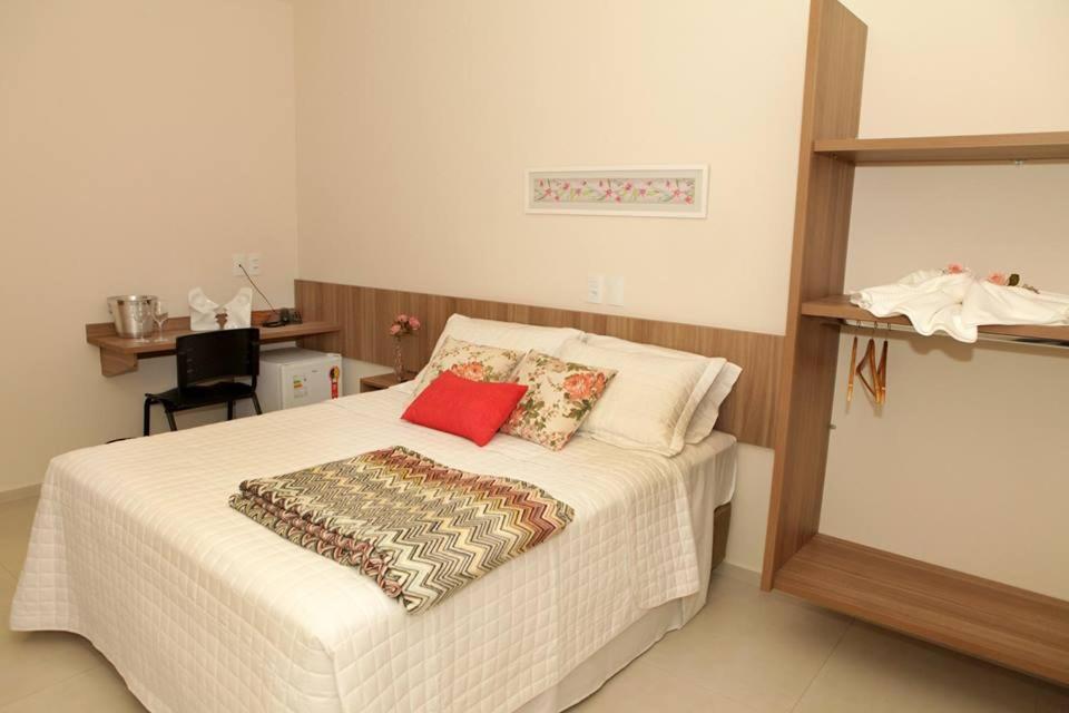 a bedroom with a white bed with a red pillow at Siena Hotel in Pederneiras