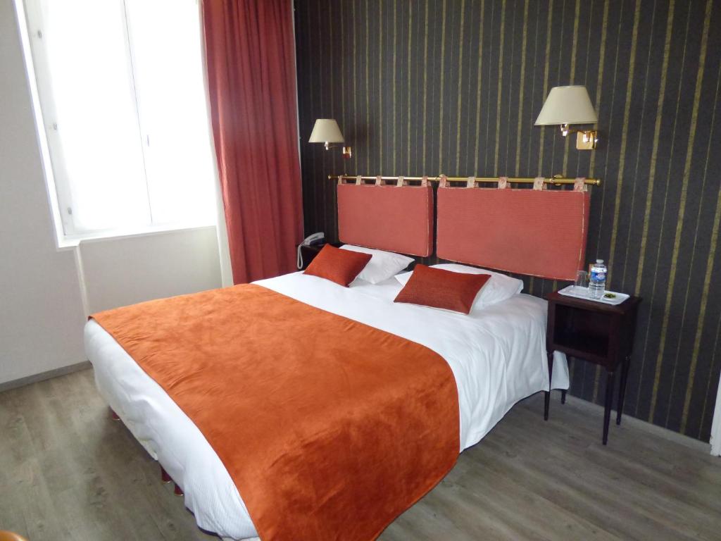 Logis Au Grand Hotel في مايين: غرفة فندق بسرير كبير مع بطانية برتقال