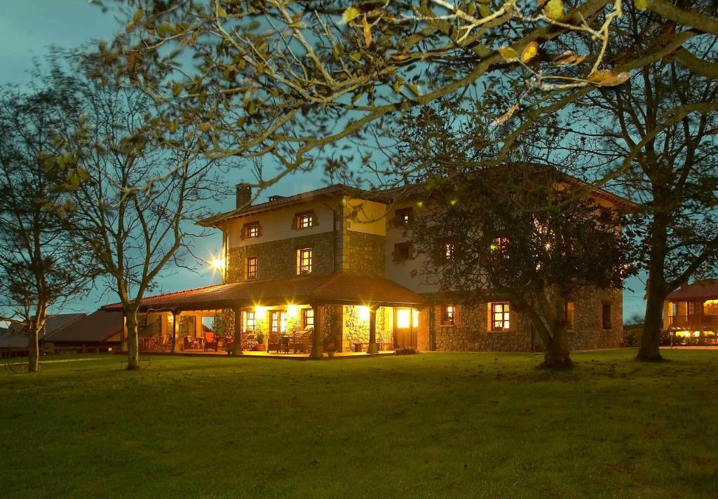 una casa grande con sus luces encendidas por la noche en Posada Caborredondo, en Oreña