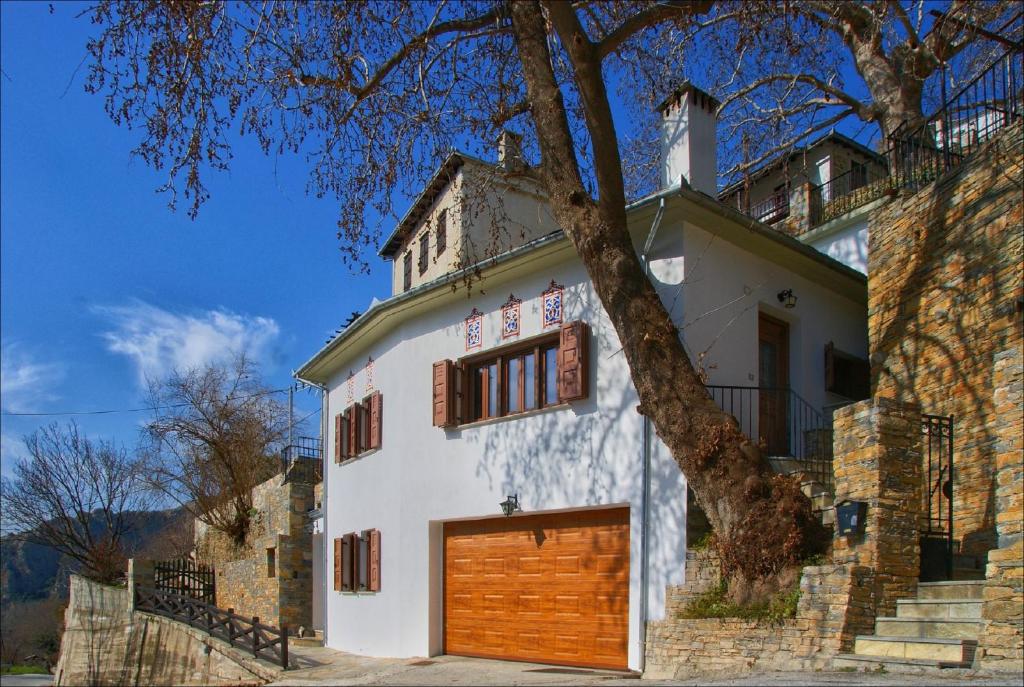 a white house with a brown garage door at Volos View Residence in Makrinítsa