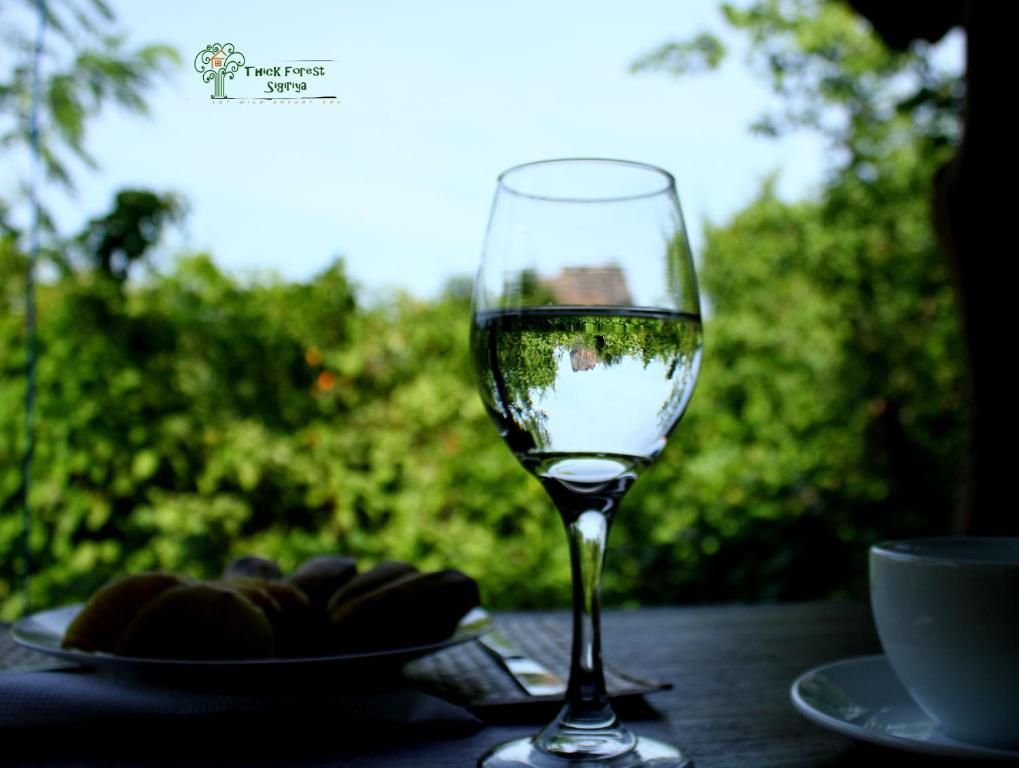 a glass of white wine sitting on a table at The Thick Forest in Sigiriya