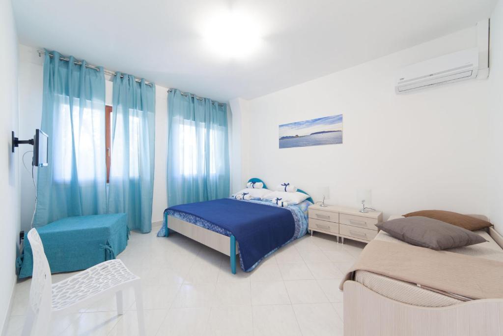 a bedroom with two beds and blue curtains at Appartamenti DueC in Trapani