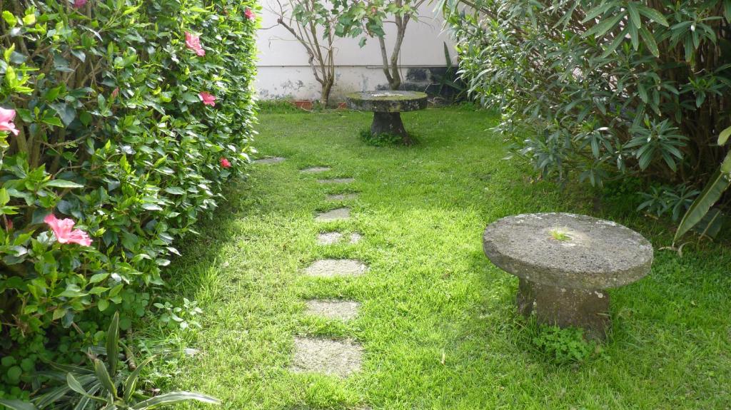 a stone path with a bench in a garden at AZORES GARDEN HOUSE - Suites B&B and Private Apartments - Self Access KEYBOARD in Ponta Delgada