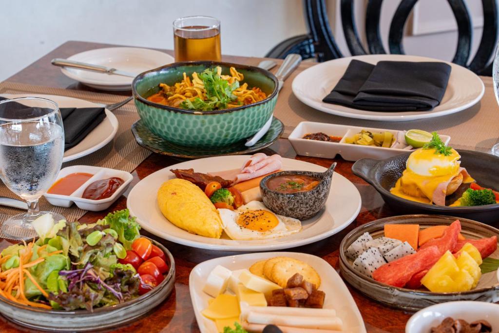 A close view of a multi-dish breakfast with noodles, eggs, fruit and salad.