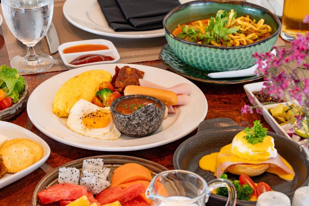 A close-up breakfast spread with eggs, fruit, salad, noodles and pastries.