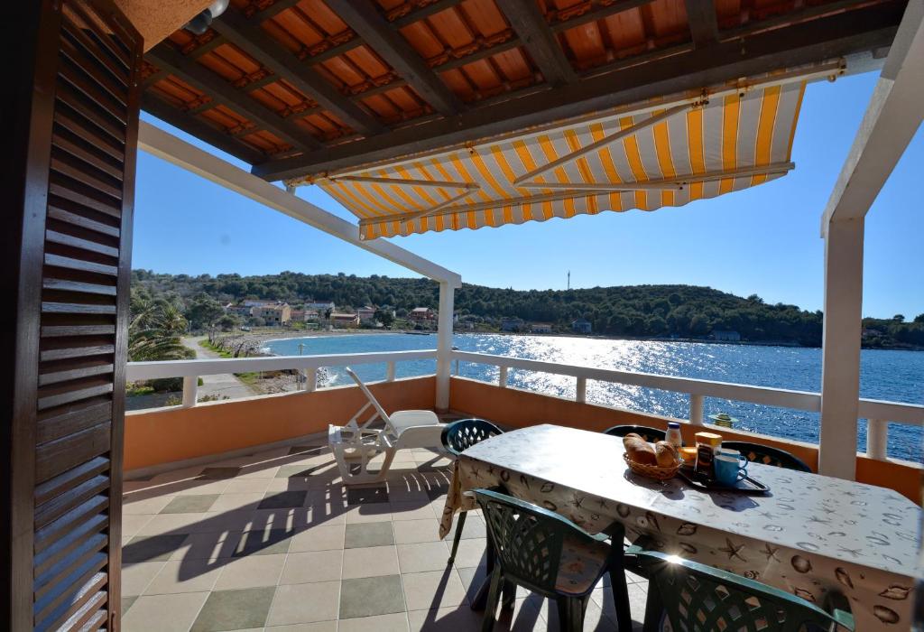 einen Balkon mit einem Tisch und Stühlen sowie Blick auf das Wasser in der Unterkunft Apartments SOL in Soline
