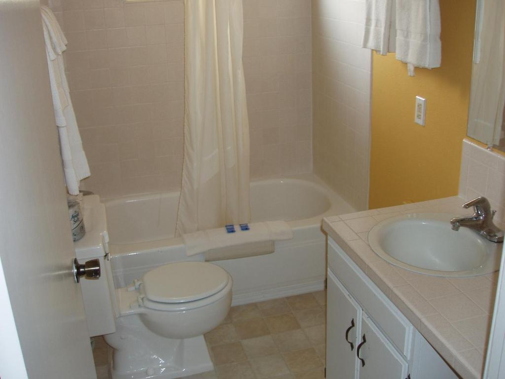 a bathroom with a toilet and a sink and a tub at Ocean Shores Inn & Suites in Ocean Shores