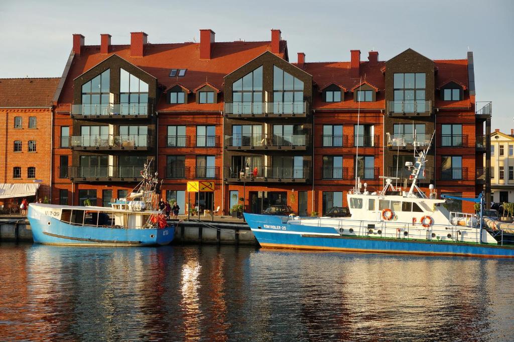 two boats in the water in front of a building at Bulwar Słońca in Ustka