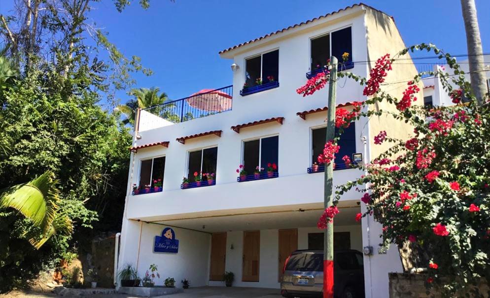 a white building with flowers in front of it at Hotel Quinta Mar y Selva in Chacala