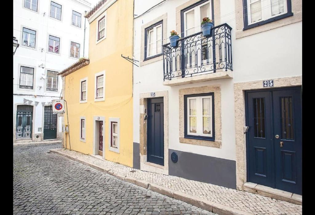een geplaveide straat met gele en witte gebouwen bij Atalaia Home in Lissabon