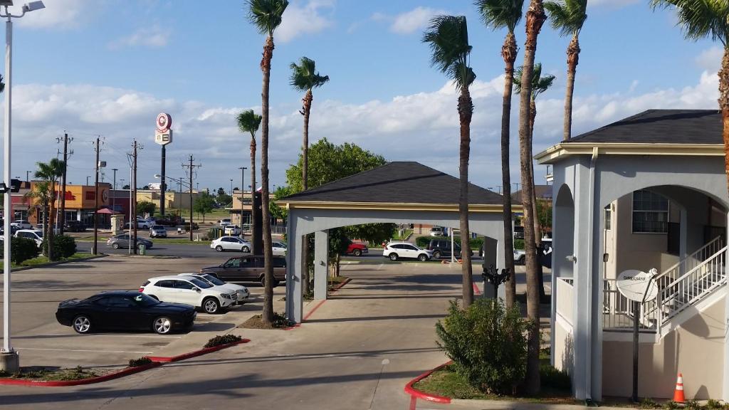 un estacionamiento con coches estacionados en un estacionamiento con palmeras en Texas Inn Downtown McAllen en McAllen