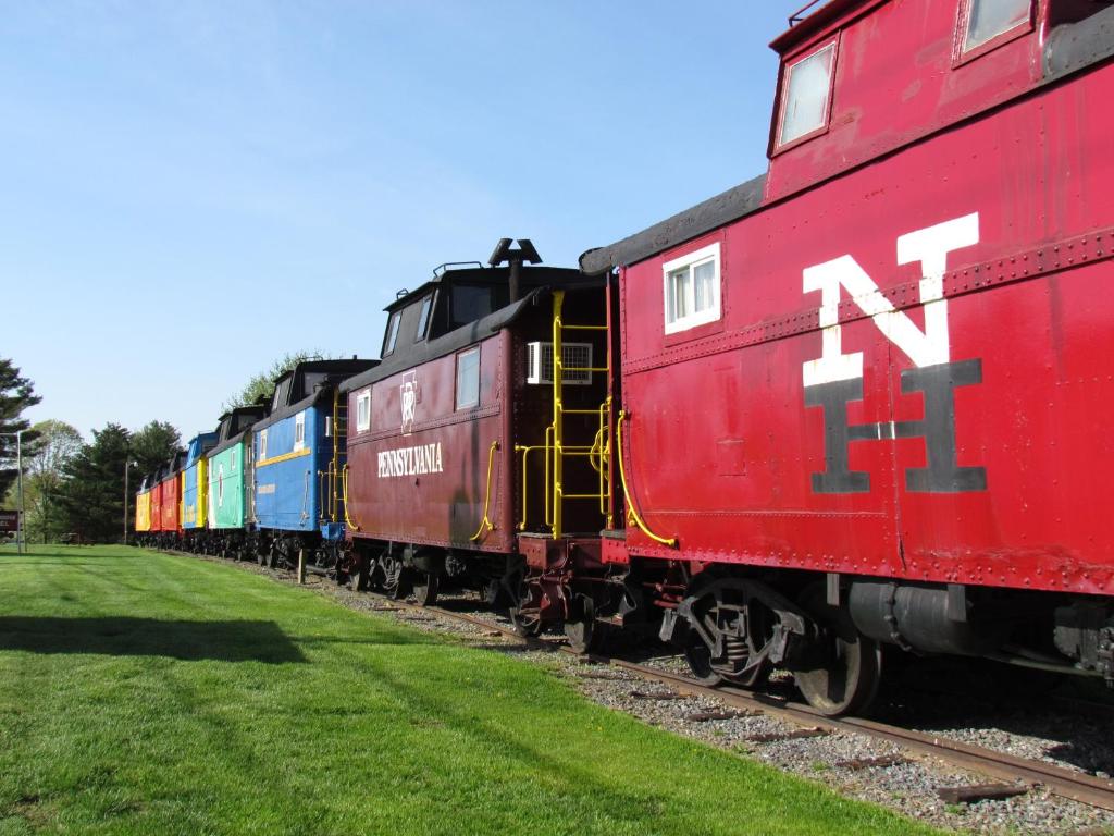 un tren rojo con autos coloridos en las vías en Red Caboose Motel & Restaurant, en Ronks