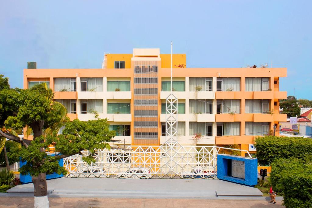 un bâtiment avec une clôture blanche devant lui dans l'établissement Hotel del Parque, à Ciudad del Carmen