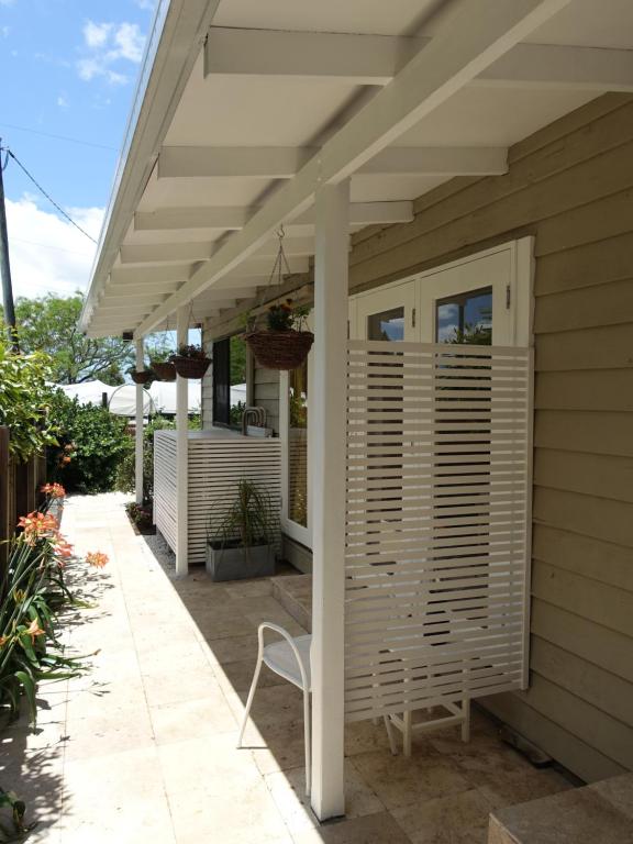 een patio met een witte pergola en een stoel bij Winston Cottage in Palmwoods