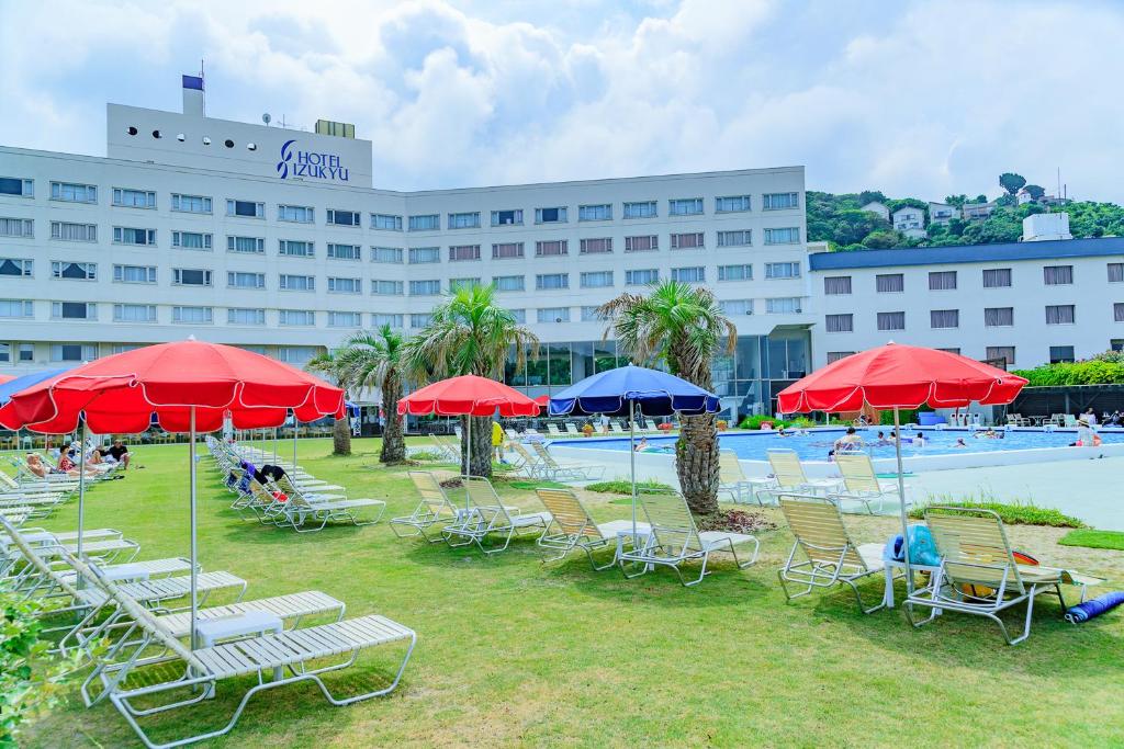 a group of chairs and umbrellas in front of a hotel at Hotel Izukyu in Shimoda