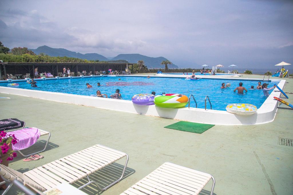 a large swimming pool with people in the water at Hotel Izukyu in Shimoda