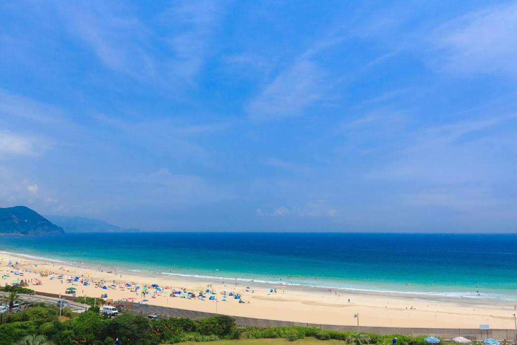 a group of people on a beach with the ocean at Hotel Izukyu in Shimoda