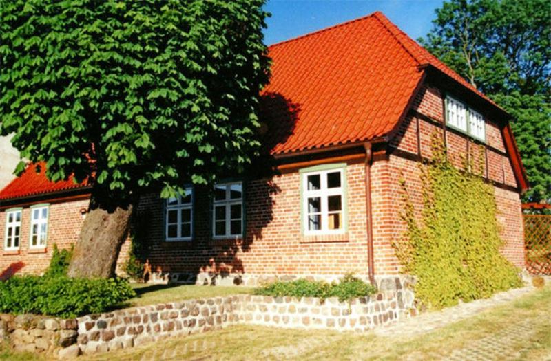 ein Backsteinhaus mit einem orangenen Dach und einem Baum in der Unterkunft Ferienhaus mit 3 Schlafräumen Neu Sommersdorf SCHW 891 in Sommersdorf