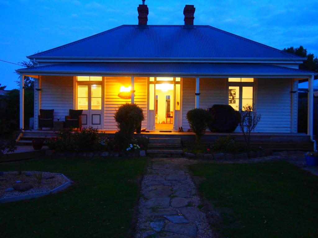 Windsor Cottage في Kingston Beach: منزل أبيض مع الأضواء في الليل