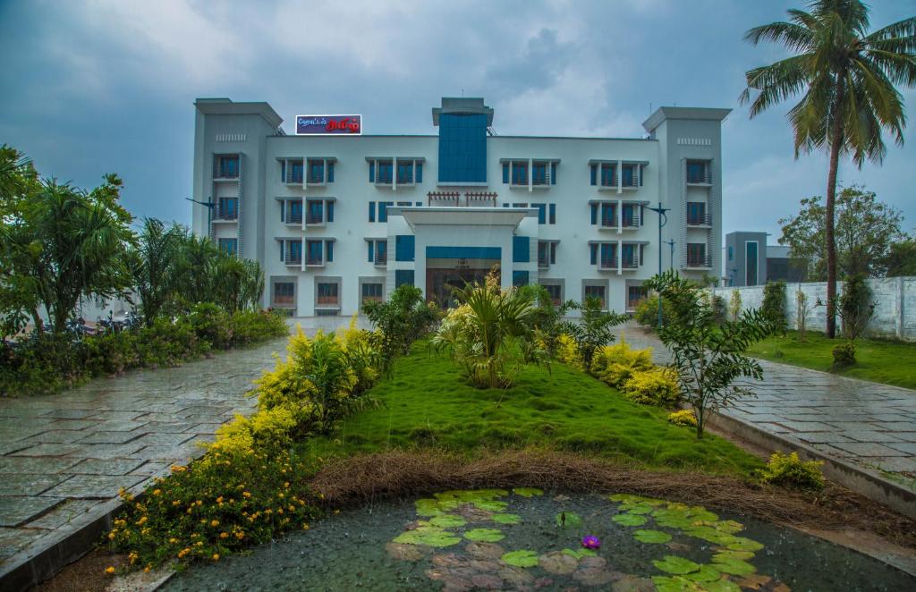 a building with a pond in front of it at Hotel Amil in Rājapālaiyam