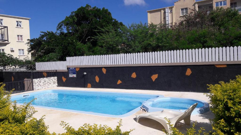 uma piscina com uma cadeira ao lado de uma cerca em Ashmara Villa & Studio em Flic-en-Flac