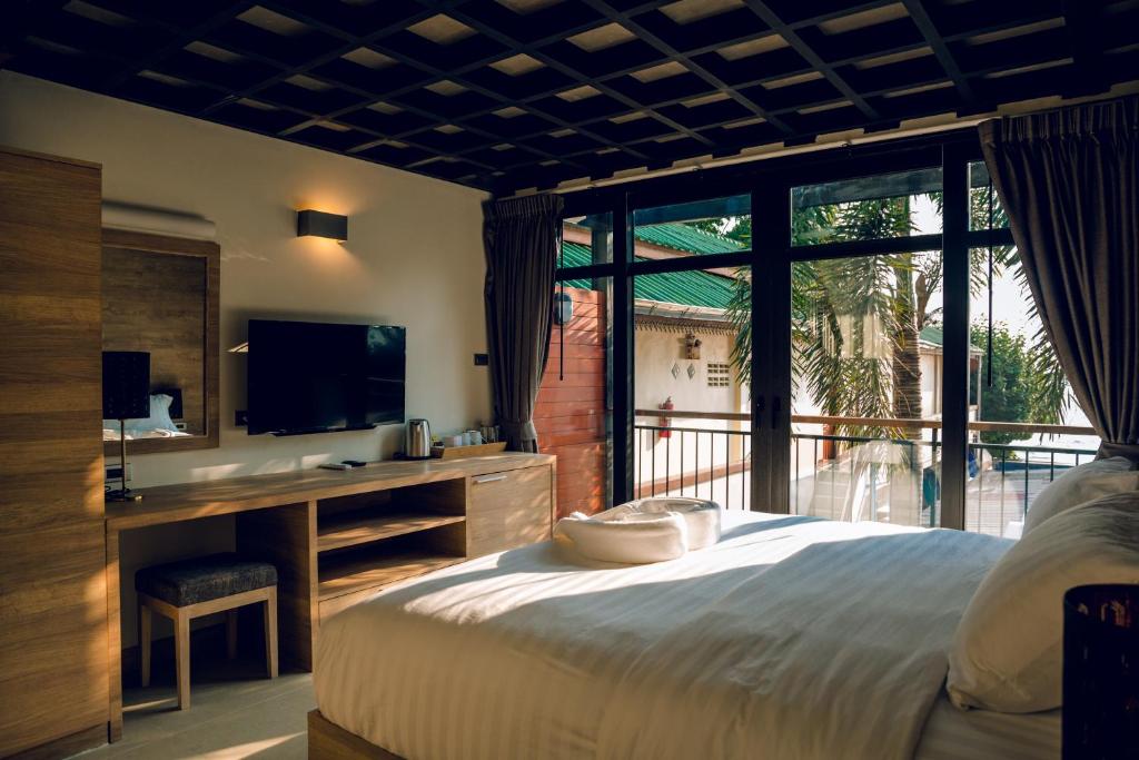 a bedroom with a bed and a tv and a window at 15 Palms Beach Resort in Ko Chang